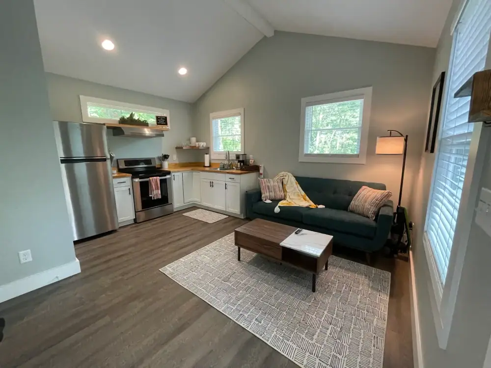Open living room and kitchen with sage gray walls, white trim and a vaulted white ceiling